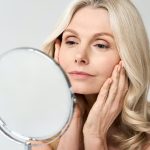 closeup-portrait-middle-age-50-woman-looking-at-mirror-touching-healthy-skin-.jpg